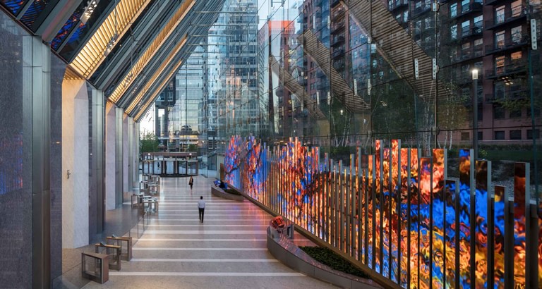 The media wall lit in oranges and blues along the full length of the lobby, beneath the angled soffit.