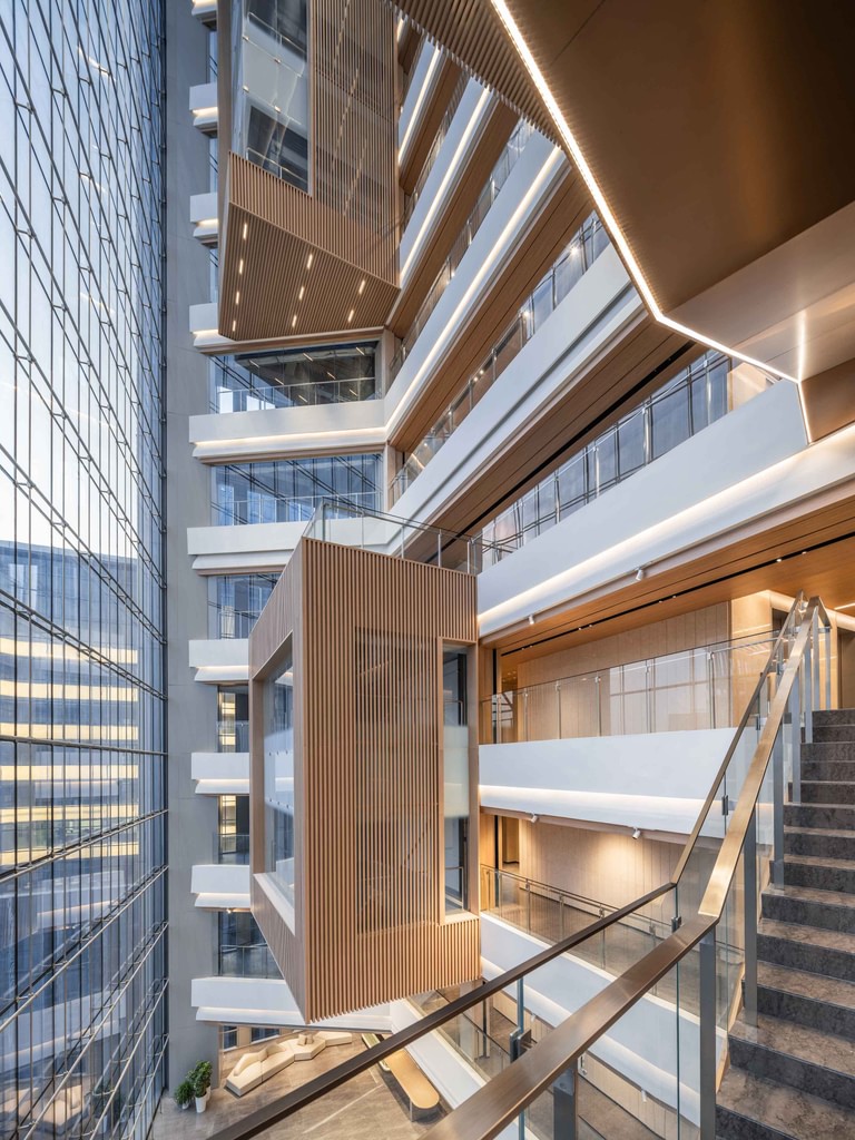 The atrium seen across the void, stacked balconies with slatted timber meeting rooms projecting into the space.
