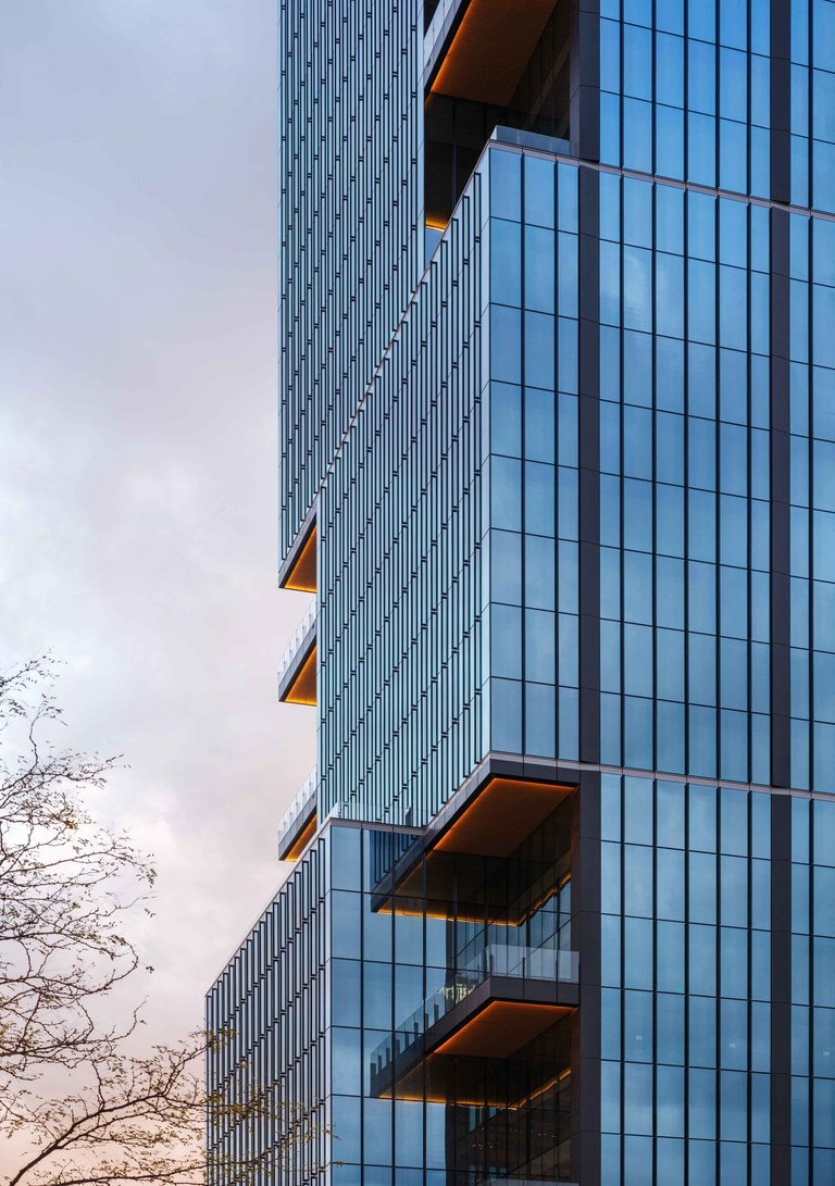 Looking up at a massing shift, the terrace soffits stacked one above the next behind the line of vertical fins.