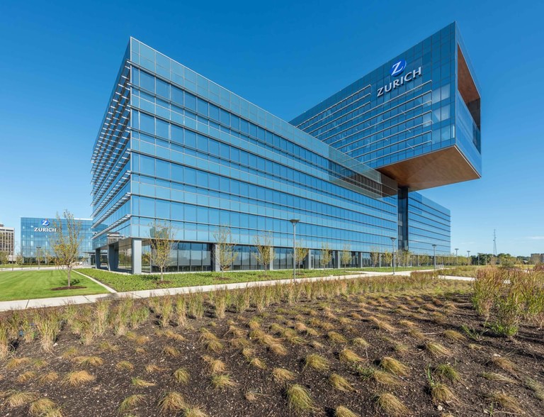 The full massing in daylight from the southwest, the cantilever and the horizontal sunshade grid above newly planted prairie.